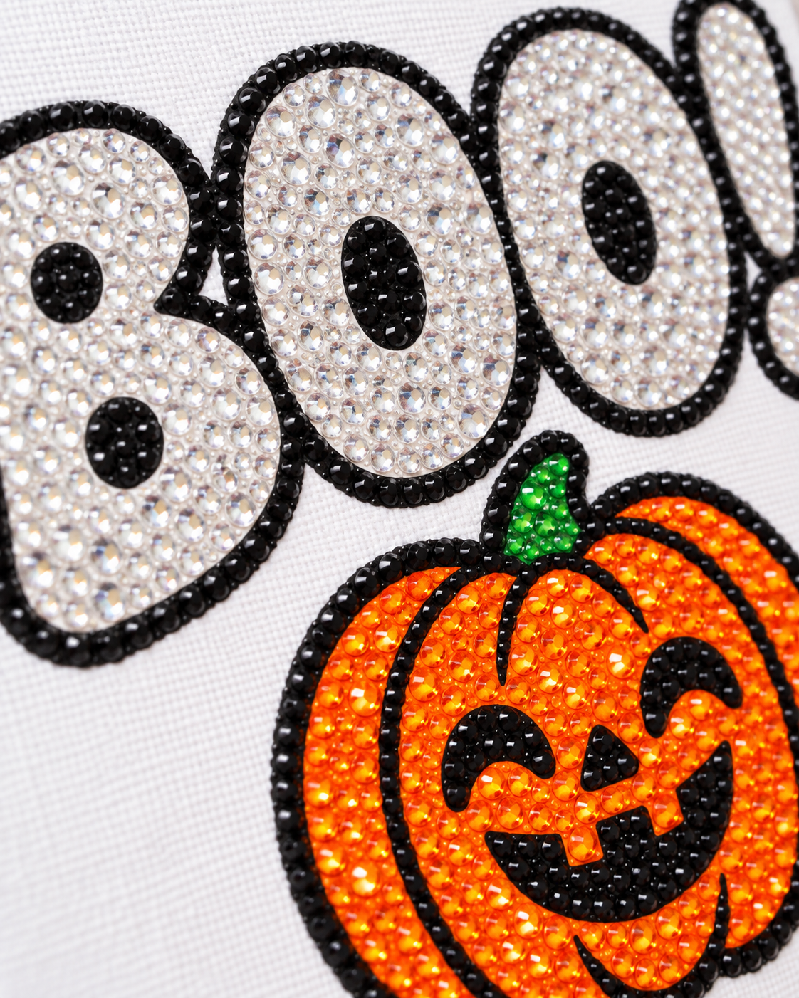 Close-up of clear black orange and green rhinestones on BOO Pumpkin canvas