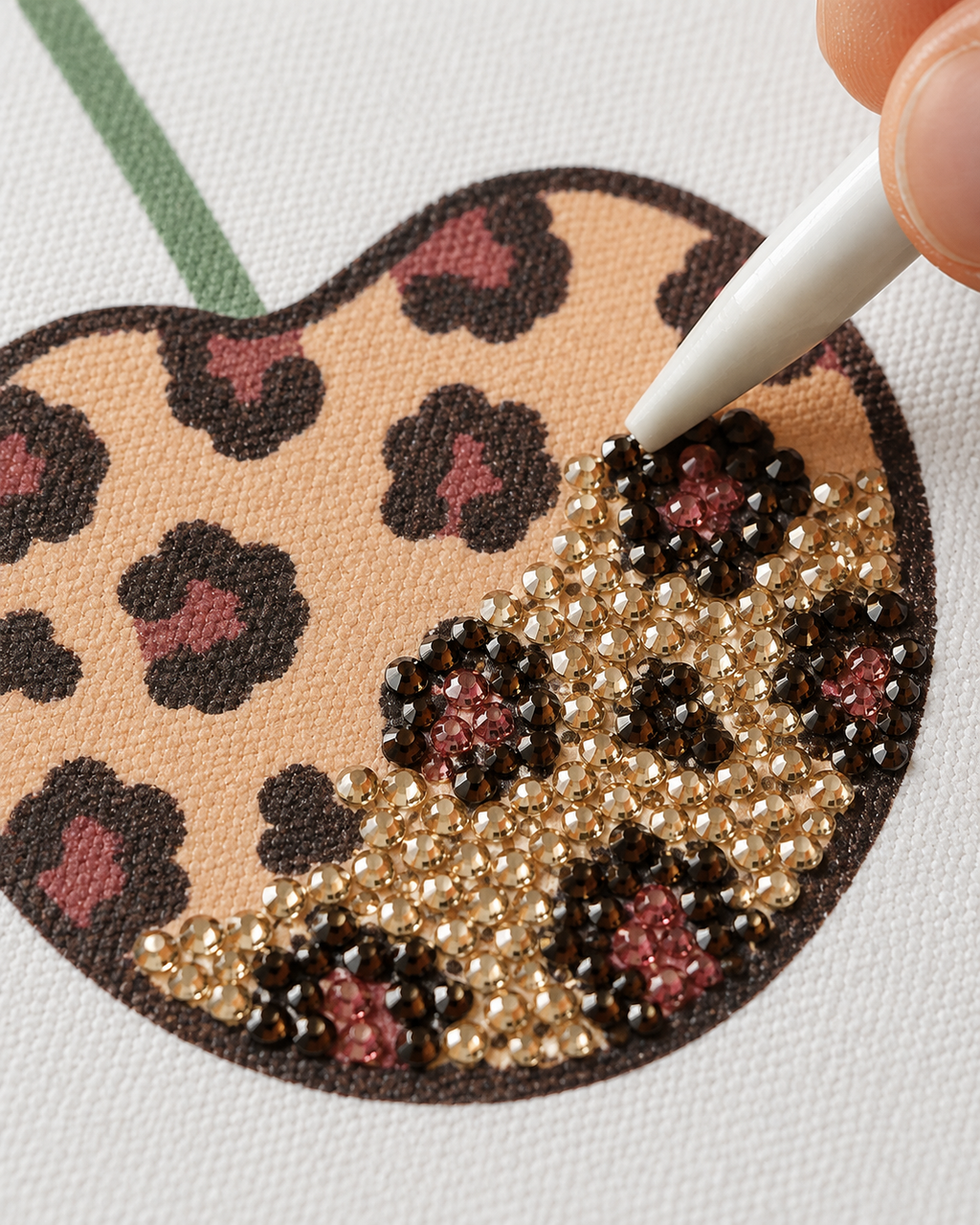 Close-up of rhinestones being placed on the Cherry Cheetah printed canvas