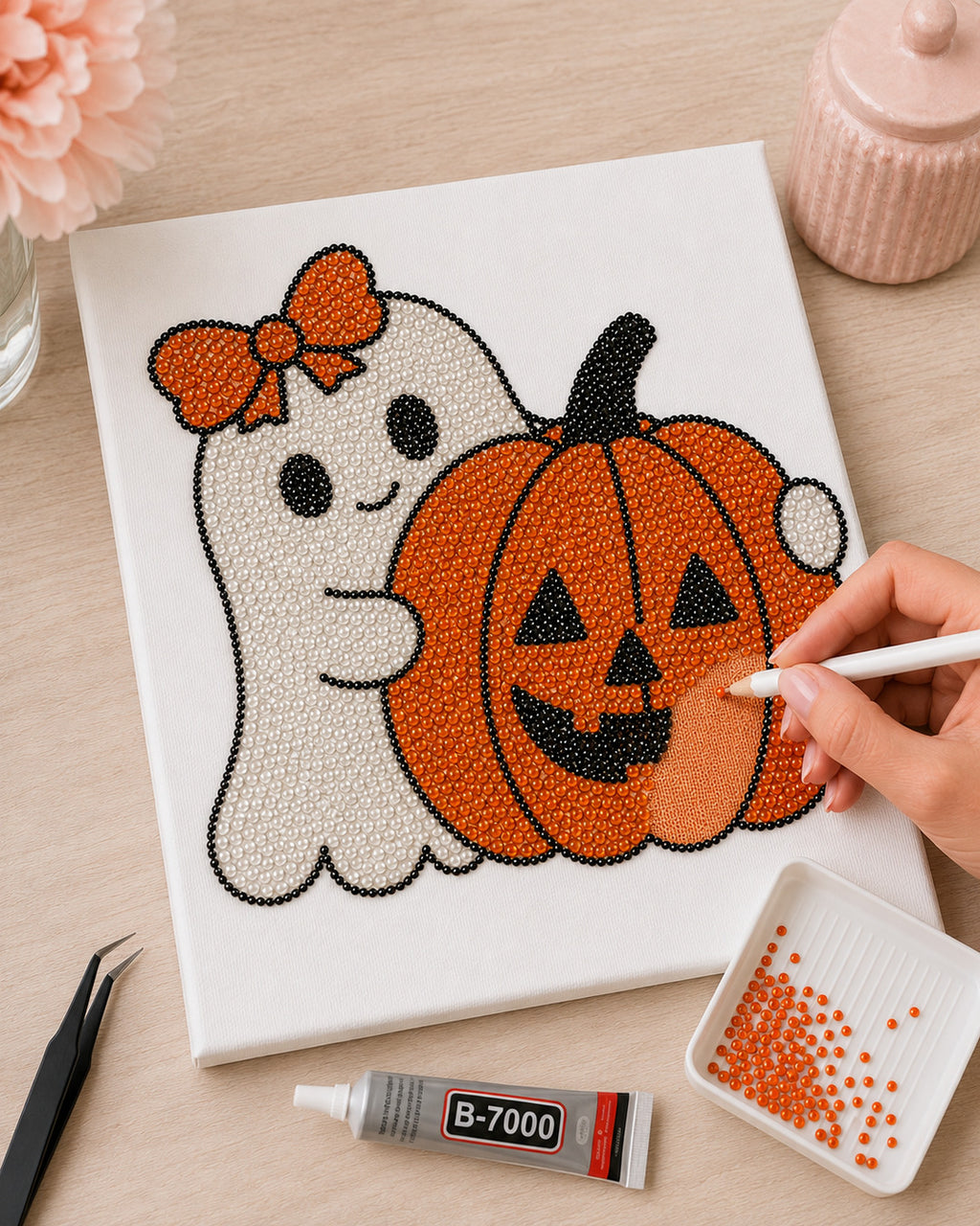 Pumpkin Boo DIY bedazzle canvas in progress with orange rhinestones and tools